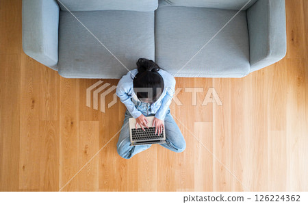 Top view of young Asian woman sitting on the floor and working on computer laptop 126224362