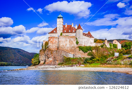 Austria, Schonbuhel Castle stands atop a rocky cliff, surrounded by golden autumn foliage, overlooking the Danube River, Wachau Valley. 126224612