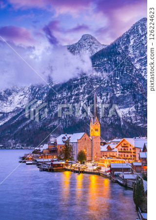 Hallstatt, Austria. Serene Alpine village with snow-covered rooftops on tranquil lake, breathtaking mountain backdrop winter twilight Hallstatt, Austria. Serene Alpine village with snow-covered rooftops on tranquil lake, breathtaking mountain backdrop winter twilight 126224623