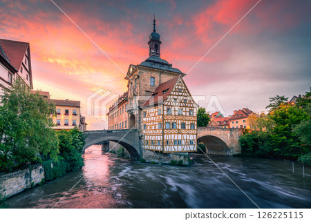 Sunset over Bamberg, Bayern - Germany, showcasing its historic architecture, vibrant skies, and peaceful river reflection 126225115