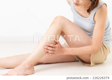 A middle-aged woman in summer clothes who is concerned about her leg body care 126226374