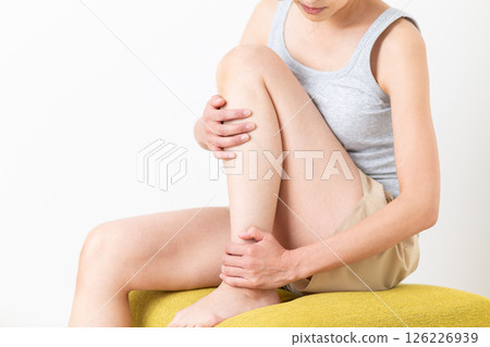 A middle-aged woman in summer clothes who is concerned about her leg body care 126226939