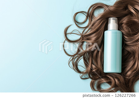 Minimalistic composition featuring a blue shampoo bottle and elegant brown hair strands on turquoise. The image emphasizes beauty, haircare, and luxury with a clean and modern aesthetic. 126227266