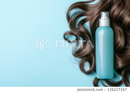 Minimalistic composition featuring a blue shampoo bottle and elegant brown hair strands on turquoise. The image emphasizes beauty, haircare, and luxury with a clean and modern aesthetic. 126227267
