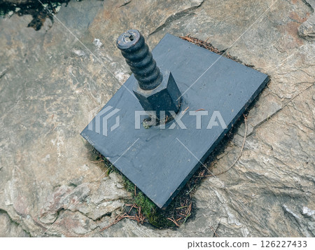 Plate and anchor bolt. Structural support on natural stone with gap to plate and anchor bolt in rocky base 126227433