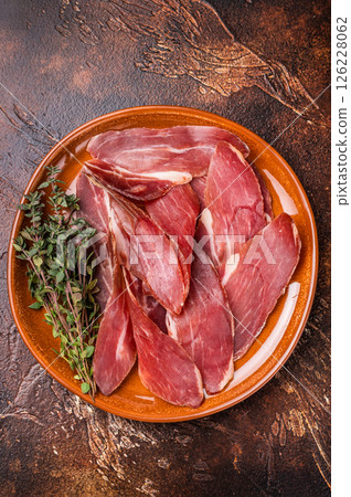 Balkan Prsut prshut, sliced cured pork meat ham on plate. brown background. top view 126228062