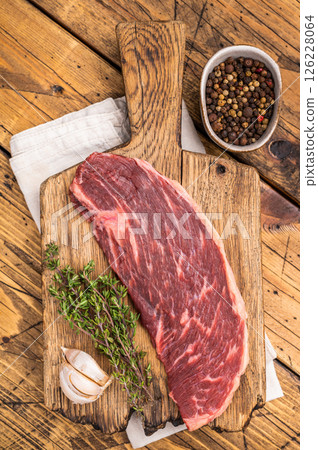 Raw rump cap steak, uncooked beef meat, showcasing its rich marbling and vibrant color. wooden background. top view 126228064