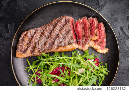 BBQ roast Rump Cap beef steak, Brazilian Picanha with salad on a plate. black background. top view 126228182