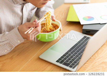 A middle-aged man eating cup ramen while working in the office 126228231