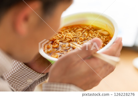 Middle-aged man eating cup ramen Middle-aged man eating cup ramen 126228276