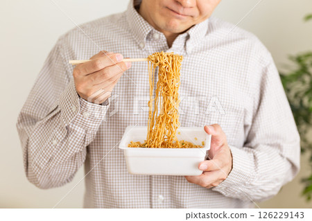 A middle-aged man wondering whether to eat cup noodles 126229143