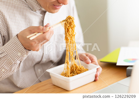 一位中年男子在辦公室工作時吃杯麵 126229209