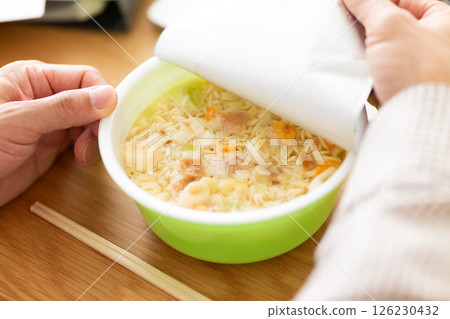 A middle-aged man eating cup ramen while working in the office 126230432