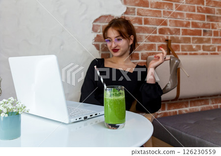 Relaxed businesswoman at cafe with laptop, smoothie and heels off 126230559