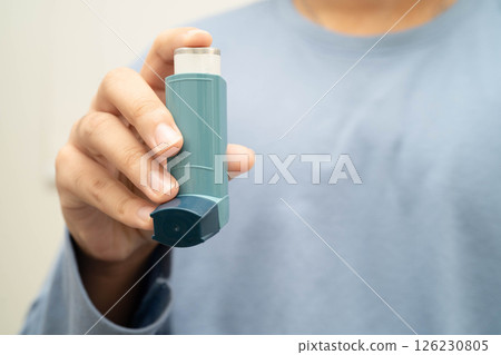 Asthma and chronic obstructive pulmonary disease COPD, Asian young man using metered dose inhaler MDI. 126230805
