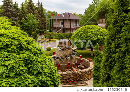 Fountain with wine barrel and glasses in lush garden landscape 126230846