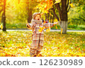 Happy child is throwing heap of maple leaves at golden autumn park background. 126230989