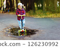 Portrait of little boy riding scooter at summer park outdoors background. 126230992