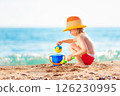 Happy child is playing with toys at sea shore background. 126230995