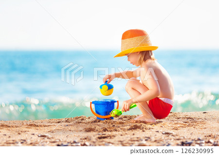 Happy child is playing with toys at sea shore background. 126230995