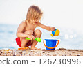 Happy child is playing with toys at sea shore background. 126230996