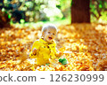 Little happy boy in yellow jacket is playing with leaves at golden autumn park background. 126230999