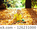 Little happy boy in yellow jacket is playing with leaves at golden autumn park background. 126231000