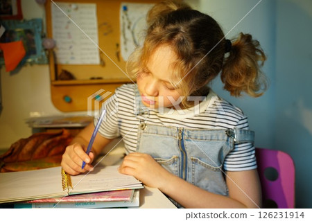 Young Girl Writing in Notebook at Desk 126231914