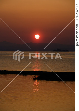 The glow of the setting sun reflected on the lake 126232514