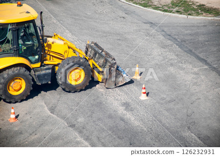 Modern yellow forklift stands on the road near the dug up road. Concept of emergency service for elimination of accident in water supply and sewerage. Copy space for text 126232931