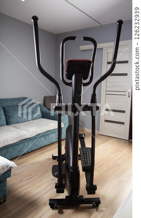Modern Elliptical Trainer in the Room at Home. Concept of Exercising at Home, fitness Modern Elliptical Trainer in the Room at Home. Concept of Exercising at Home, fitness 126232939