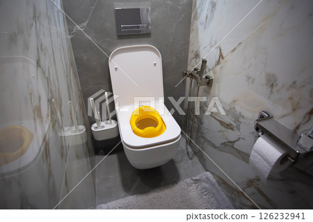 Yellow child toilet seat for children in the toilet. Convenience and comfort for the child on the toilet, close-up Yellow child toilet seat for children in the toilet. Convenience and comfort for the child on the toilet, close-up 126232941