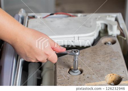 A washing machine repairman tightens the counterweight in the washing machine due to noise and vibration. Copy space for text 126232946