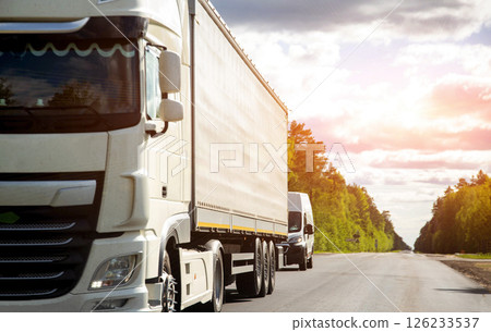 Private cargo transportation business. A modern white truck transports expensive cargo in a covered semi-trailer against the backdrop of a cloudy sky in summer. Copy sfor text. 126233537