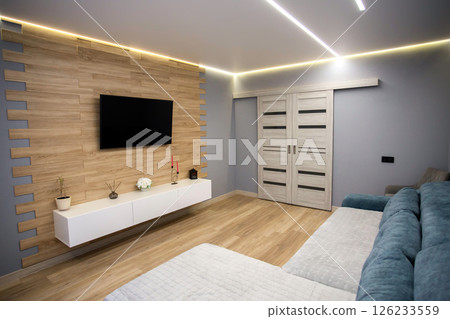 Modern interior in the living room with wooden laminate flooring, wall-hung cabinets and LCD TV. Stretch diode ceiling around the perimeter. Copy space for text, conditioner Modern interior in the living room with wooden laminate flooring, wall-hung cabinets and LCD TV. Stretch diode ceiling around the perimeter. Copy space for text, conditioner 126233559