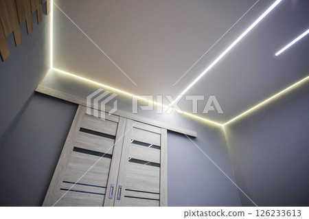 Beautiful modern stylish ceiling with light lines against the background of a sliding door in the hall. Copy space for text 126233613