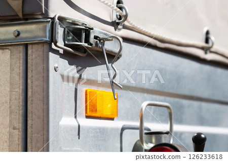 orange reflector on the side of a galvanized trailer body, close-up orange reflector on the side of a galvanized trailer body, close-up 126233618