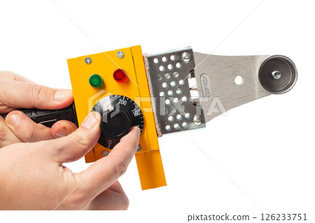 adjusting the temperature in a yellow soldering iron for soldering polypropylene pipes on a white background, isolate, close-up 126233751