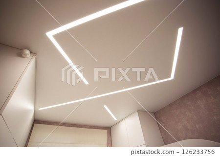 Modern designer stretch ceiling with illuminated LED lines in the room, backlighting 126233756