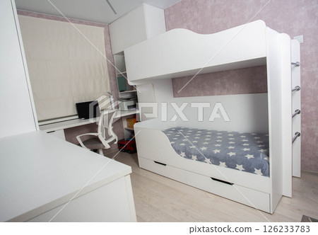 A bunk bed with a ladder in a children's modern bedroom with white furniture and interior, close-up 126233783
