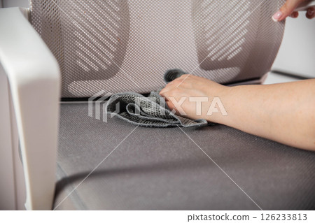 Women's hands wash dirty spots from gray upholstery of computer chair. Concept of dry cleaning of upholstered furniture at home, business, industry 126233813