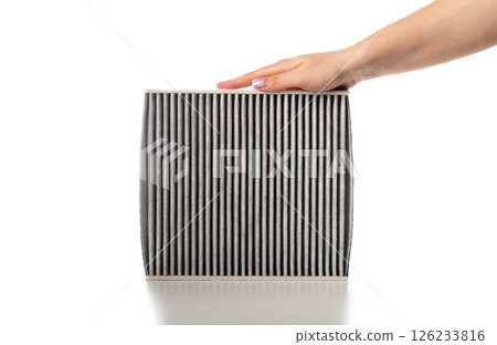 Modern carbon filter in hand for air purification in car interior on white background, isolate, close-up 126233816