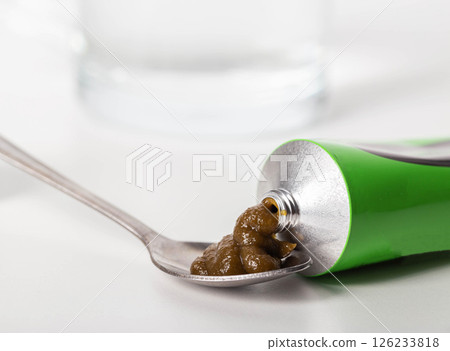 Urological paste on herbs against the background of a glass of water. Treatment of infectious inflammatory diseases of the urinary system, close-up 126233818