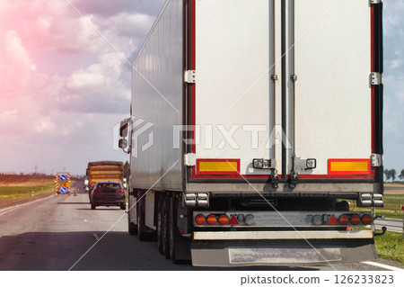 A truck with a semi-trailer delivers cargo along the highway to the marketplace. Delivery service from an online store to the buyer. Copy space for text A truck with a semi-trailer delivers cargo along the highway to the marketplace. Delivery service from an online store to the buyer. Copy space for text 126233823