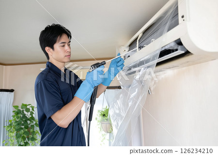 Essential before summer. Air conditioner cleaning. Male cleaning worker Essential before summer. Air conditioner cleaning. Male cleaning worker 126234210