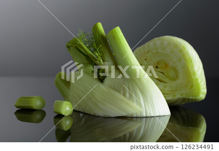 Cut fennel bulb with green stalks on a black background. 126234491