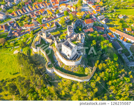 Aerial view captures the historic Rabi Castle ruins surrounded by lush greenery and a quaint village in Czechia. The remnants of the castle display its impressive architecture and rich history. Aerial view captures the historic Rabi Castle ruins surrounded by lush greenery and a quaint village in Czechia. The remnants of the castle display its impressive architecture and rich history. 126235087