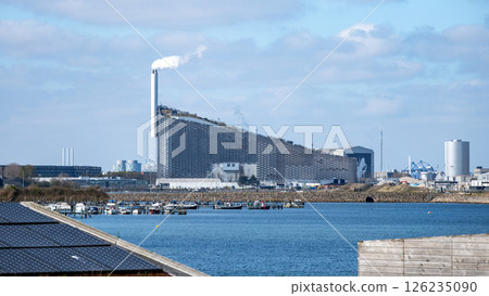Copenhill, a unique waste-to-energy plant in Copenhagen, combines function and recreation. Its distinct architecture features a sloped roof, used for skiing, with smoke rising from the chimney. Copenhill, a unique waste-to-energy plant in Copenhagen, combines function and recreation. Its distinct architecture features a sloped roof, used for skiing, with smoke rising from the chimney. 126235090