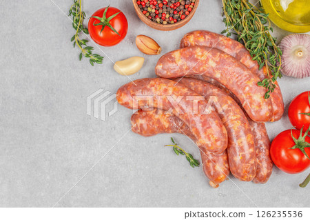 Raw butchers sausages with spices and vegetables on a light background, top view. copy space 126235536