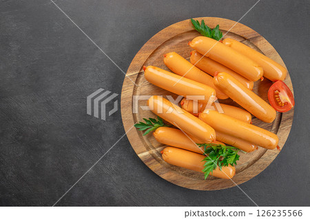 delicious boiled sausage on a wooden board, on a dark background. top view. copy space 126235566